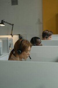 A Woman with Headset Inside a Gray Cubicle